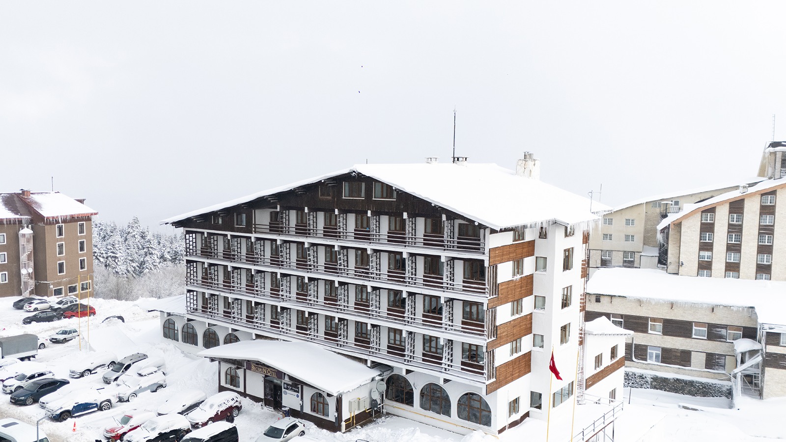 Beceren Otel's timber-banded facade under heavy snow, its sign above the entrance